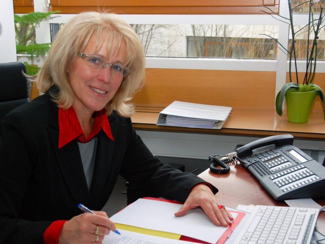 Das Foto zeigt eine Frau an einem Tisch.