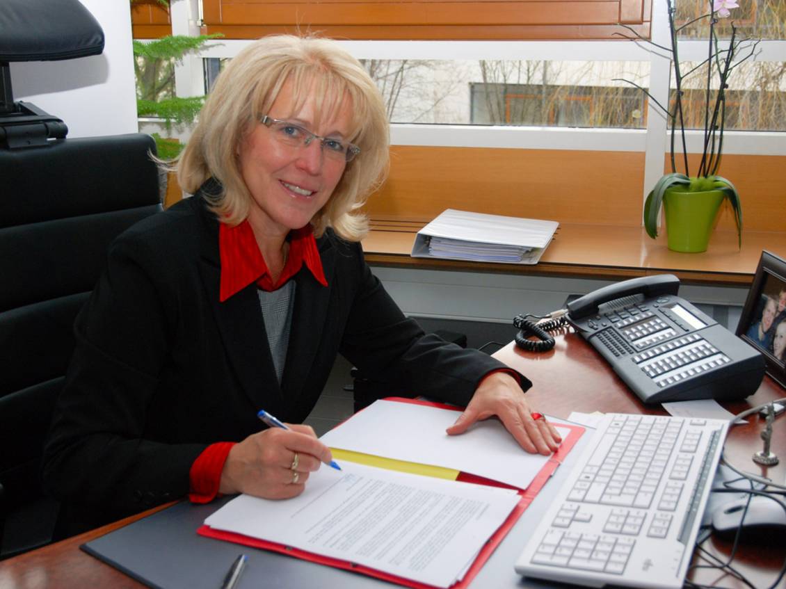 Das Foto zeigt eine Frau an einem Tisch.