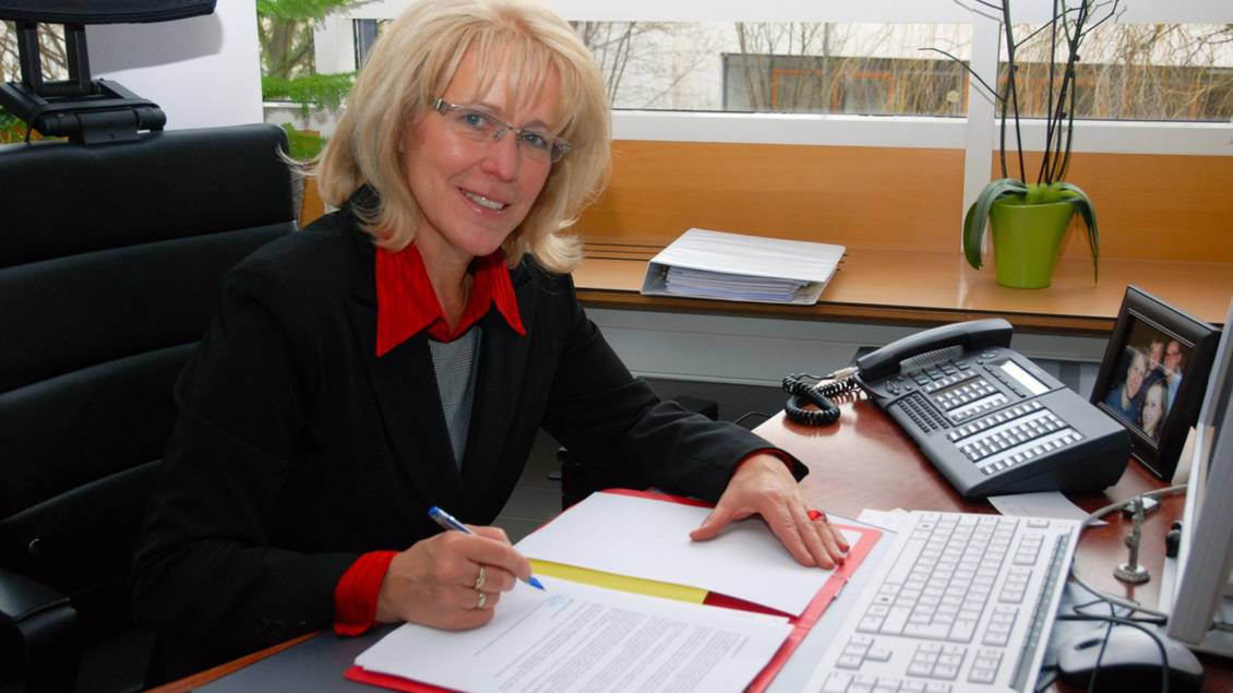 Das Foto zeigt eine Frau an einem Tisch.