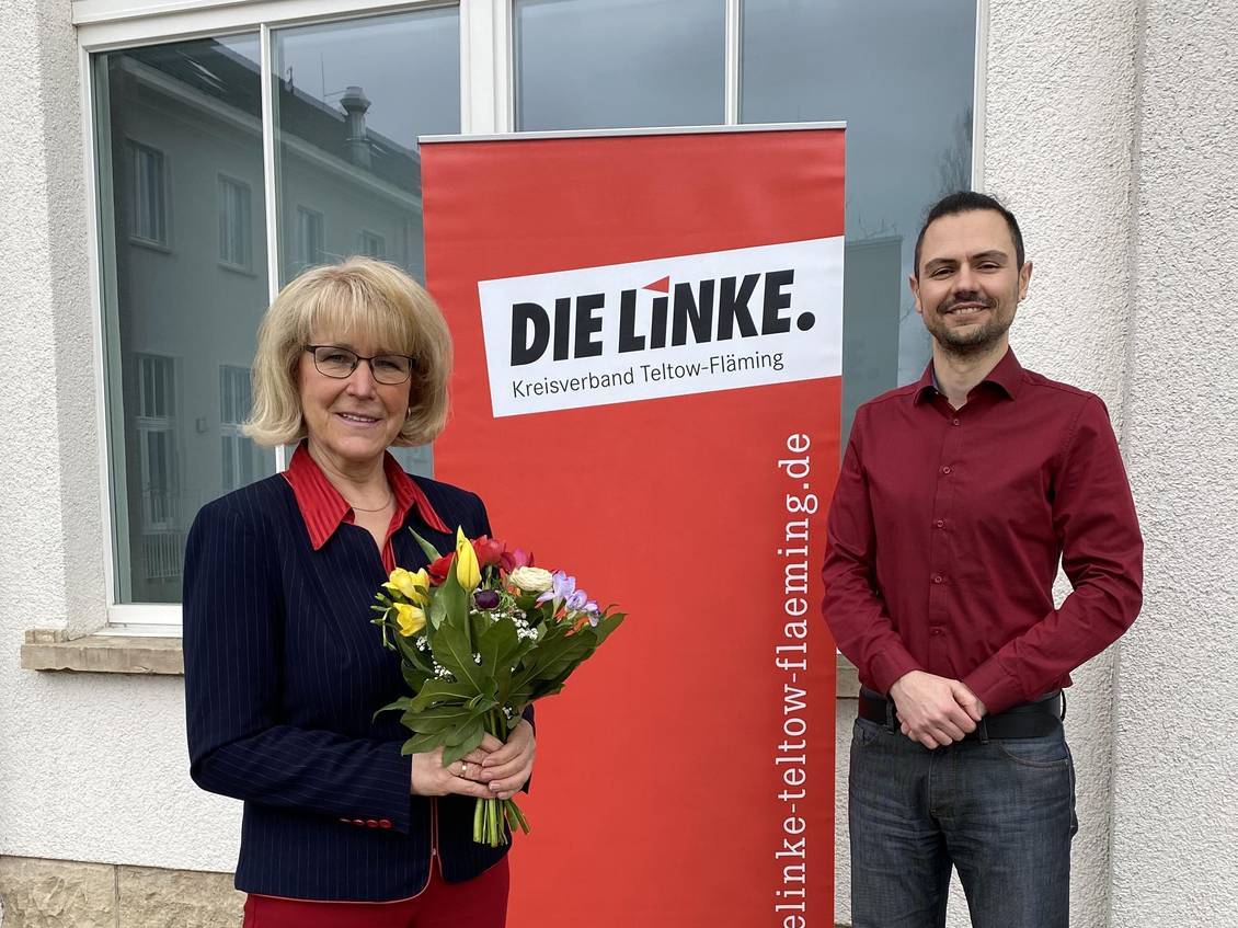 Das Foto zeigt zwei Personen vor einer Häuserwand.