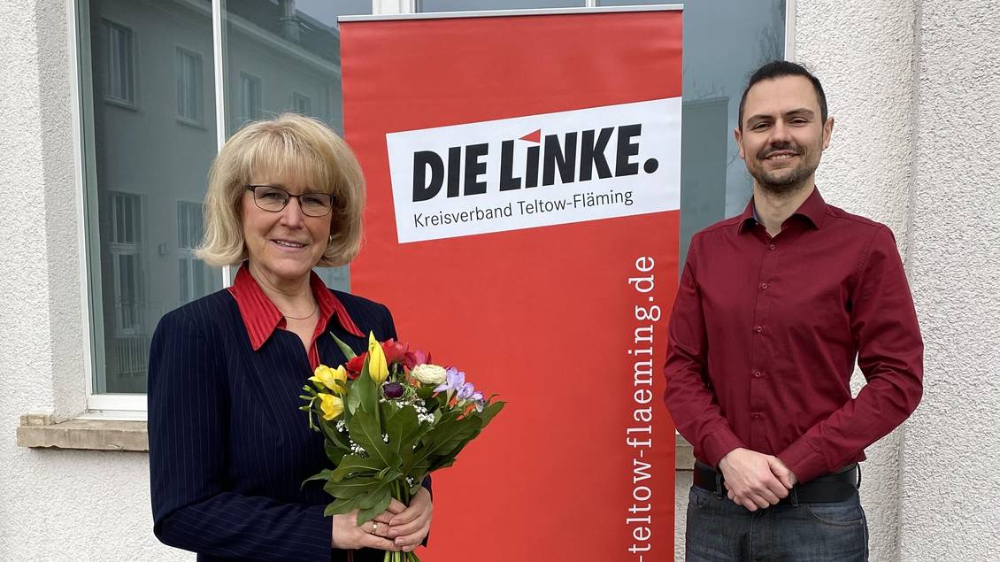 Das Foto zeigt zwei Personen vor einer Häuserwand.