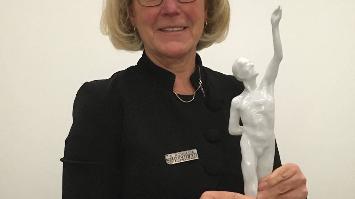 Das Foto zeigt eine Frau, die eine Porzellanfigur hält.