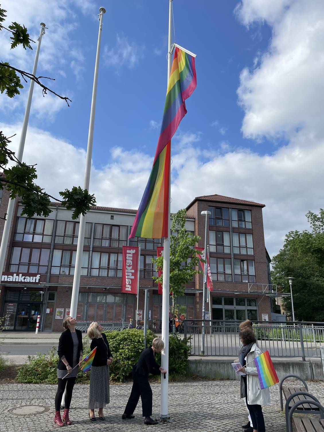 Das Foto zeigt Personen, die am Mast eine Fahne hochziehen.