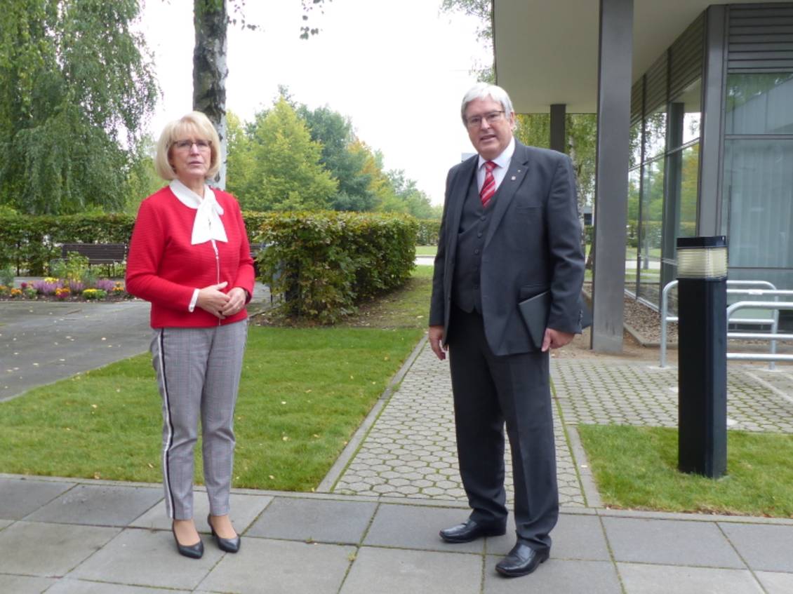 Das Foto zeigt zwei Personen vor einem Gebäude.