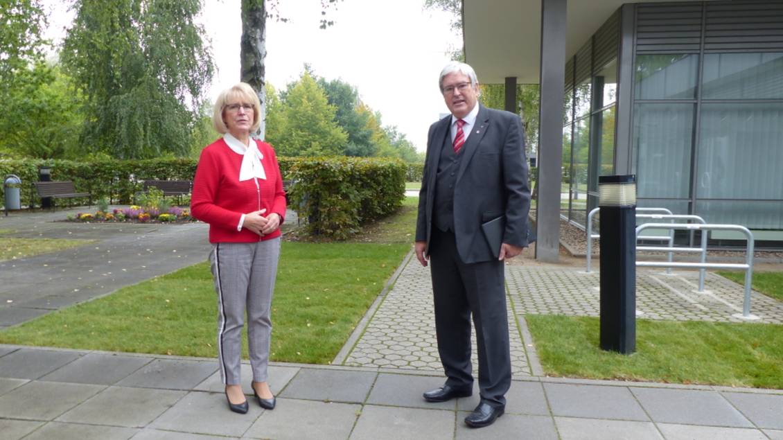 Das Foto zeigt zwei Personen vor einem Gebäude.