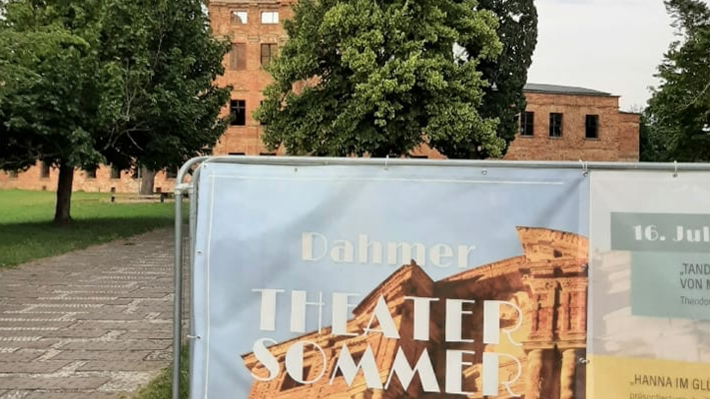 Das Foto zeigt ein Plakat und im Hintergrund die Schlossruine.