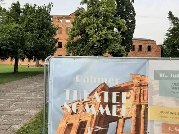Das Foto zeigt ein Plakat und im Hintergrund die Schlossruine.