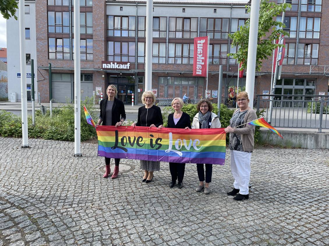 Das Foto zeigt Personen, die vor sich eine Regenbogenflagge halten.