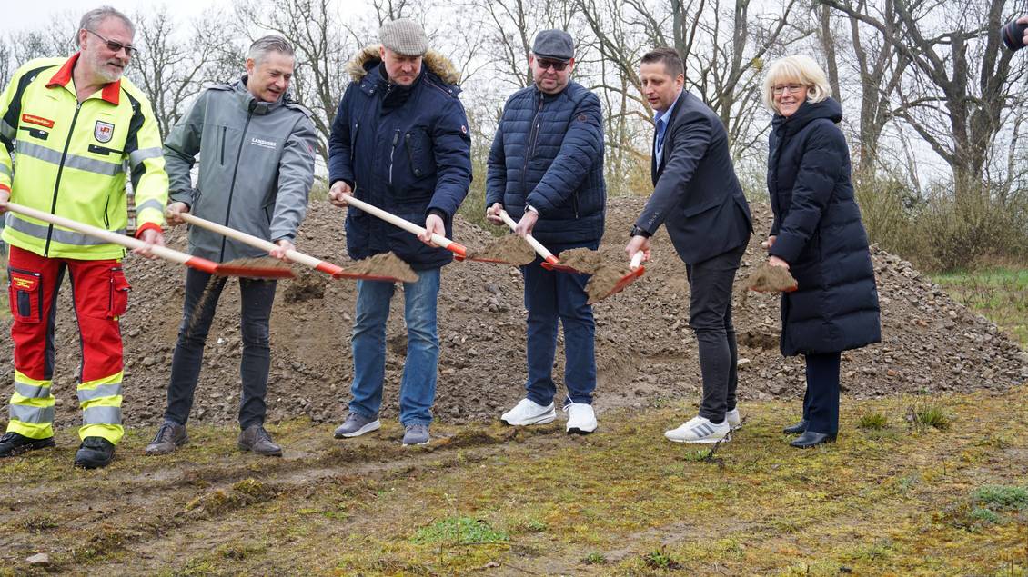 Das Foto zeigt eien Gruppe von Menschen, die mit Spaten Erde schippen.