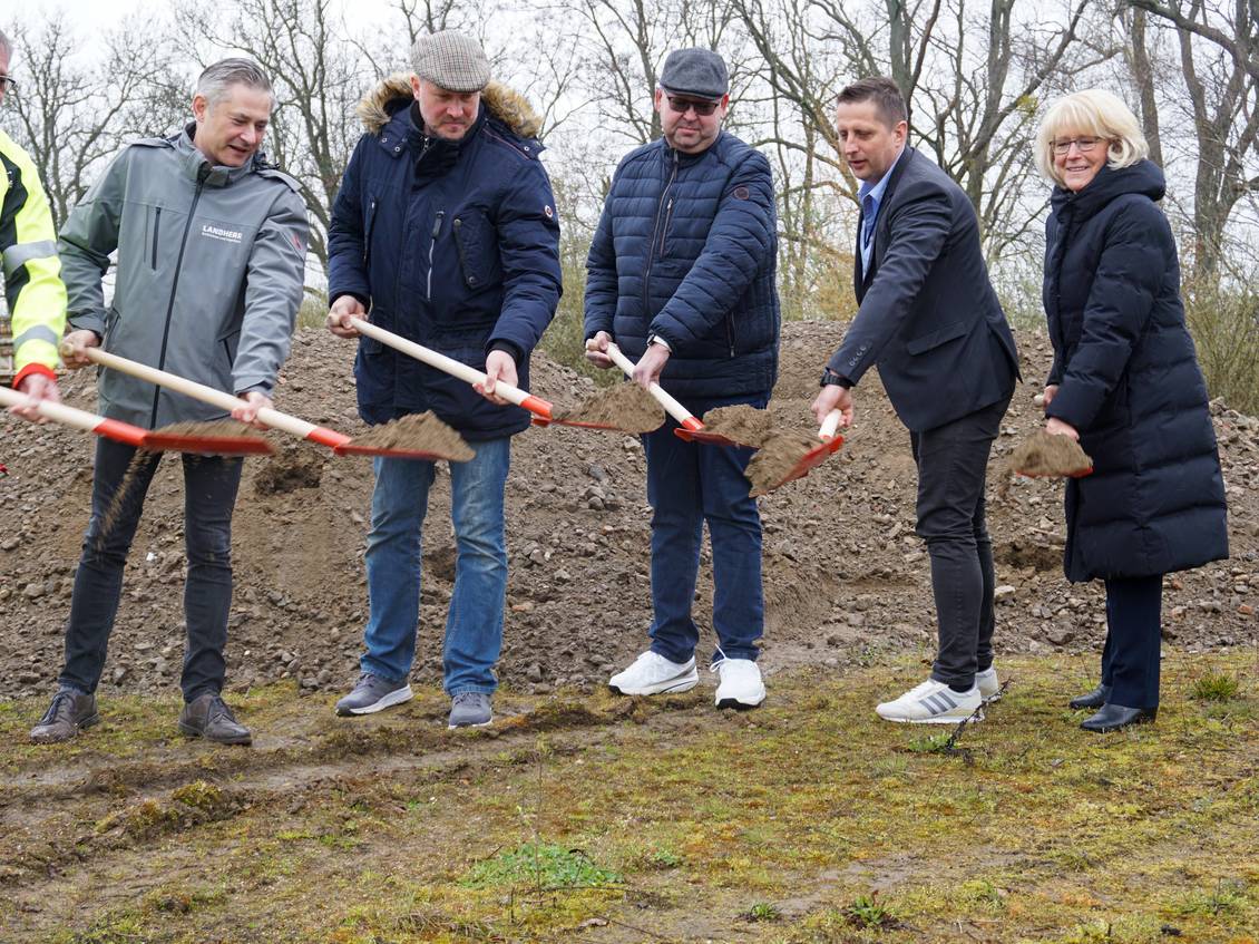 Das Foto zeigt eien Gruppe von Menschen, die mit Spaten Erde schippen.