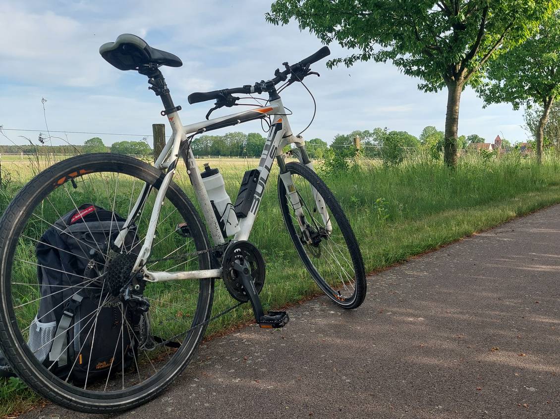 Das Foto zeigt ein abgestelltes Fahrrad an einem Radweg, daneben ein Feld.
