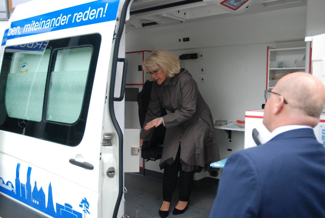 Das Foto zeigt zwei Personen bei einem Fahrzeug.