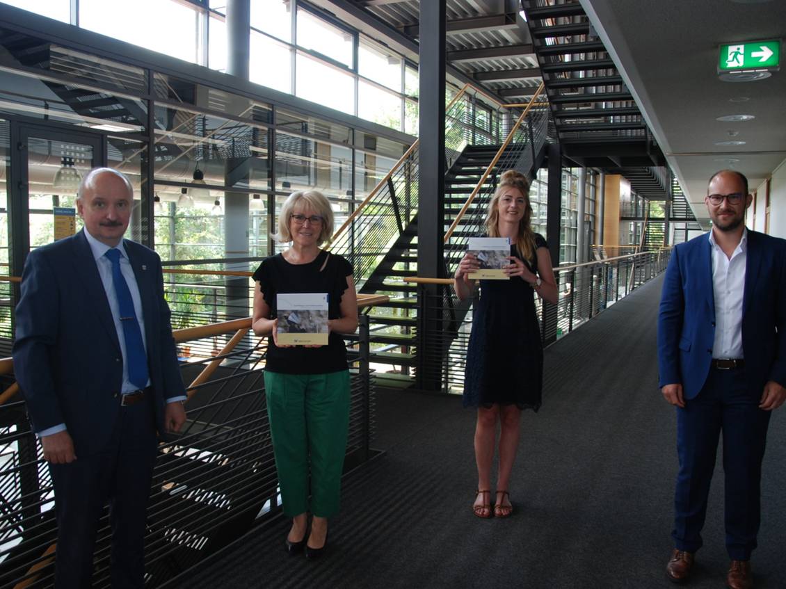 Das Foto zeigt vier Personen im Foyer des Kreishauses.