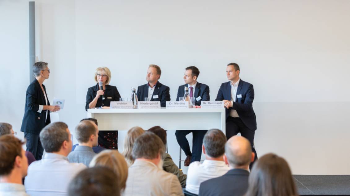 Das Foto zeigt eine Gruppe von Personen auf einem Podium vor Publikum.